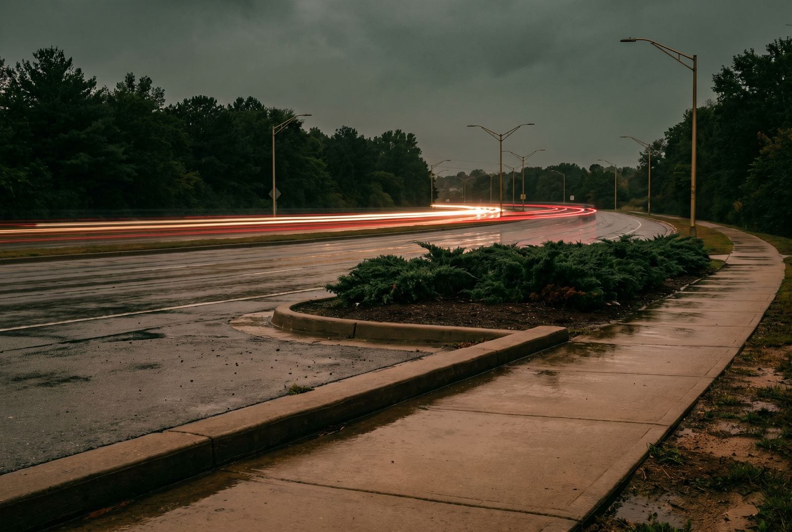 A six-lane arterial at dusk in the rain, the traffic drawn into ribbons of light