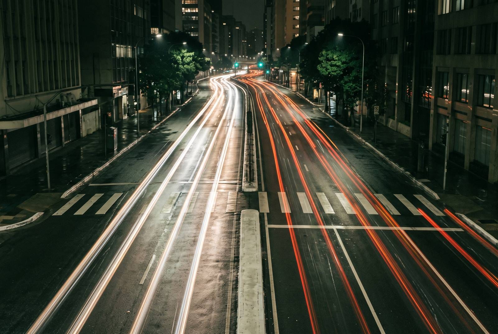 A city street at night from above, headlights drawn into unbroken streaks