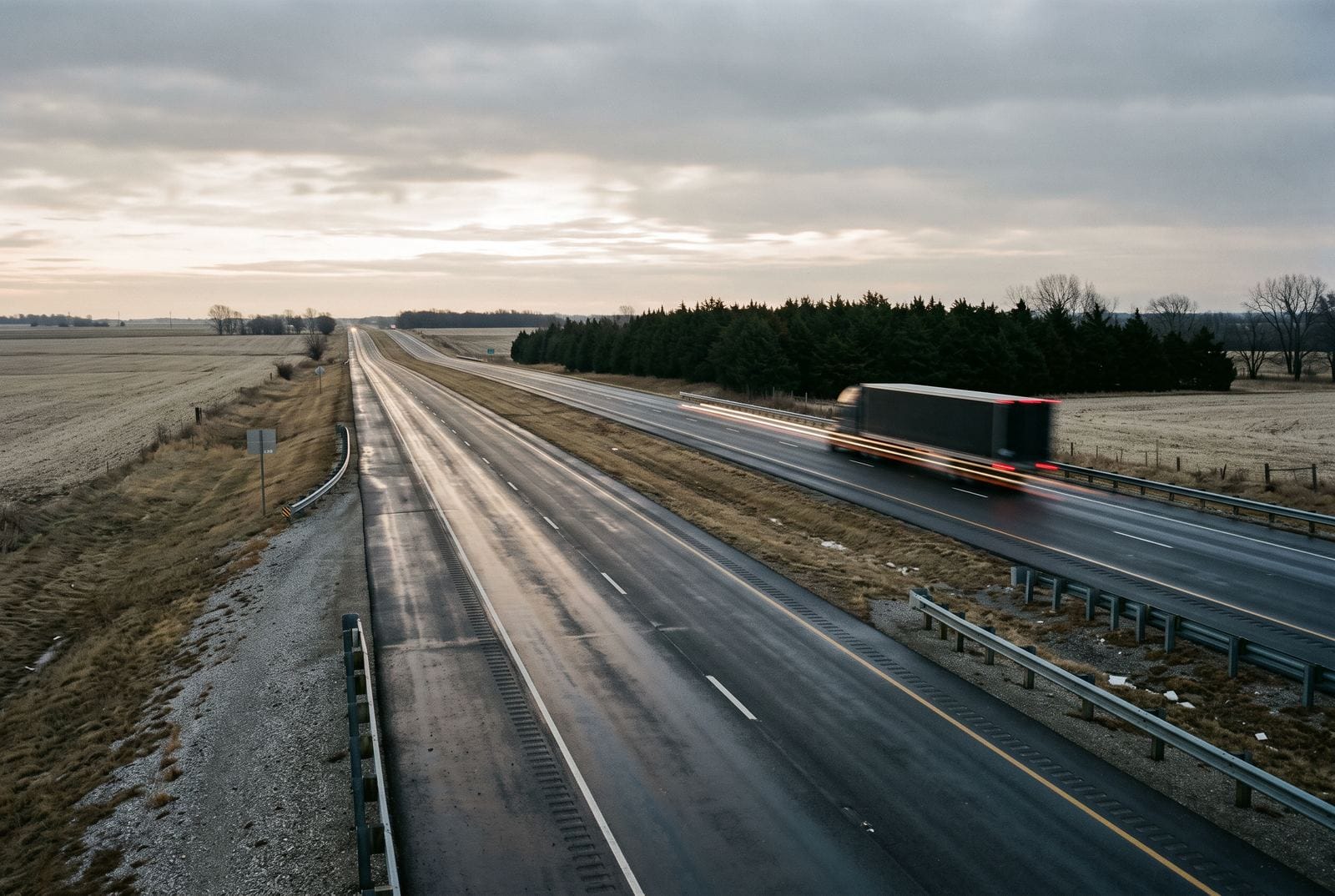 A single unmarked tractor-trailer on a divided highway seen from a long way off