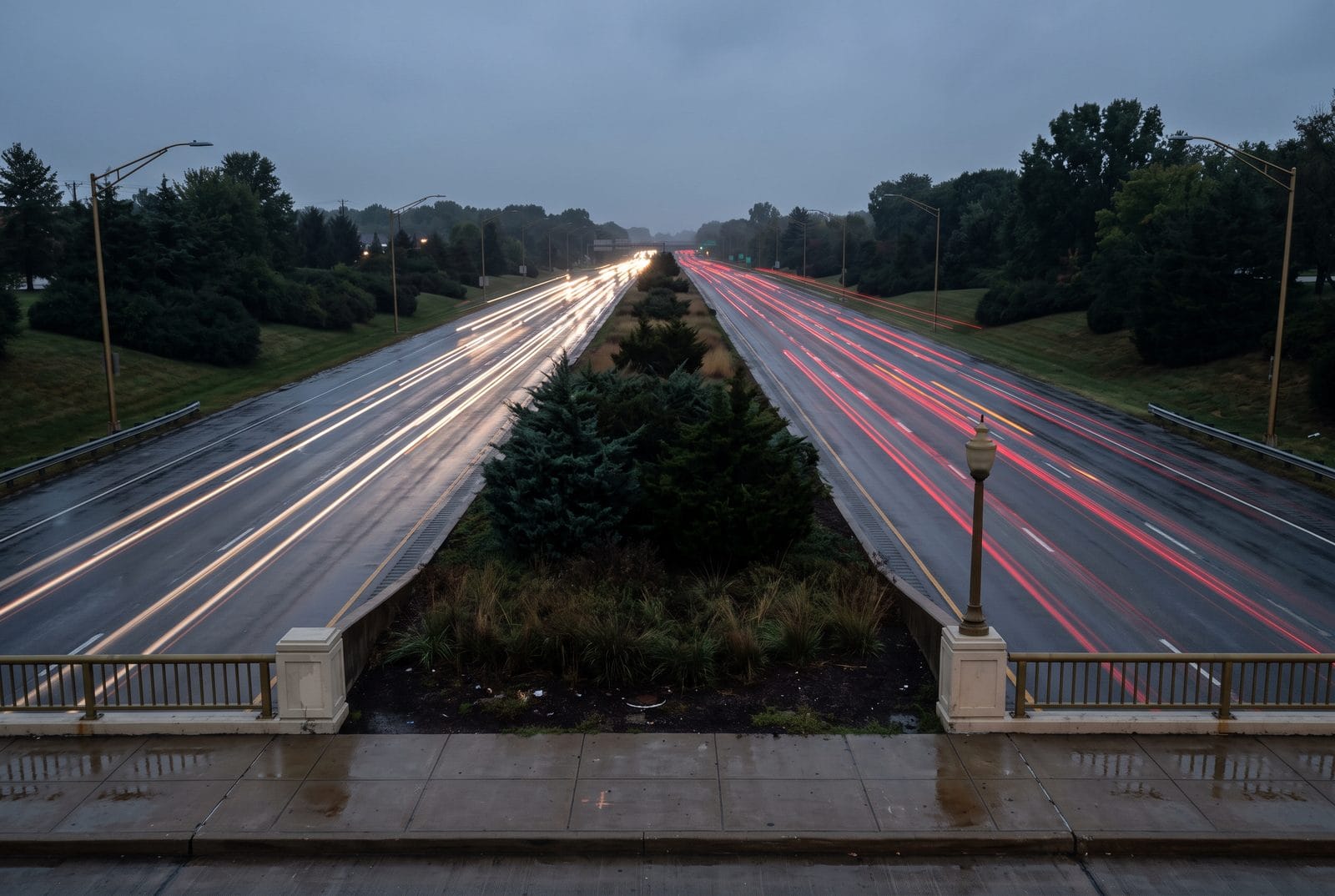 A six-lane arterial with a planted median at dusk, traffic drawn into ribbons of light
